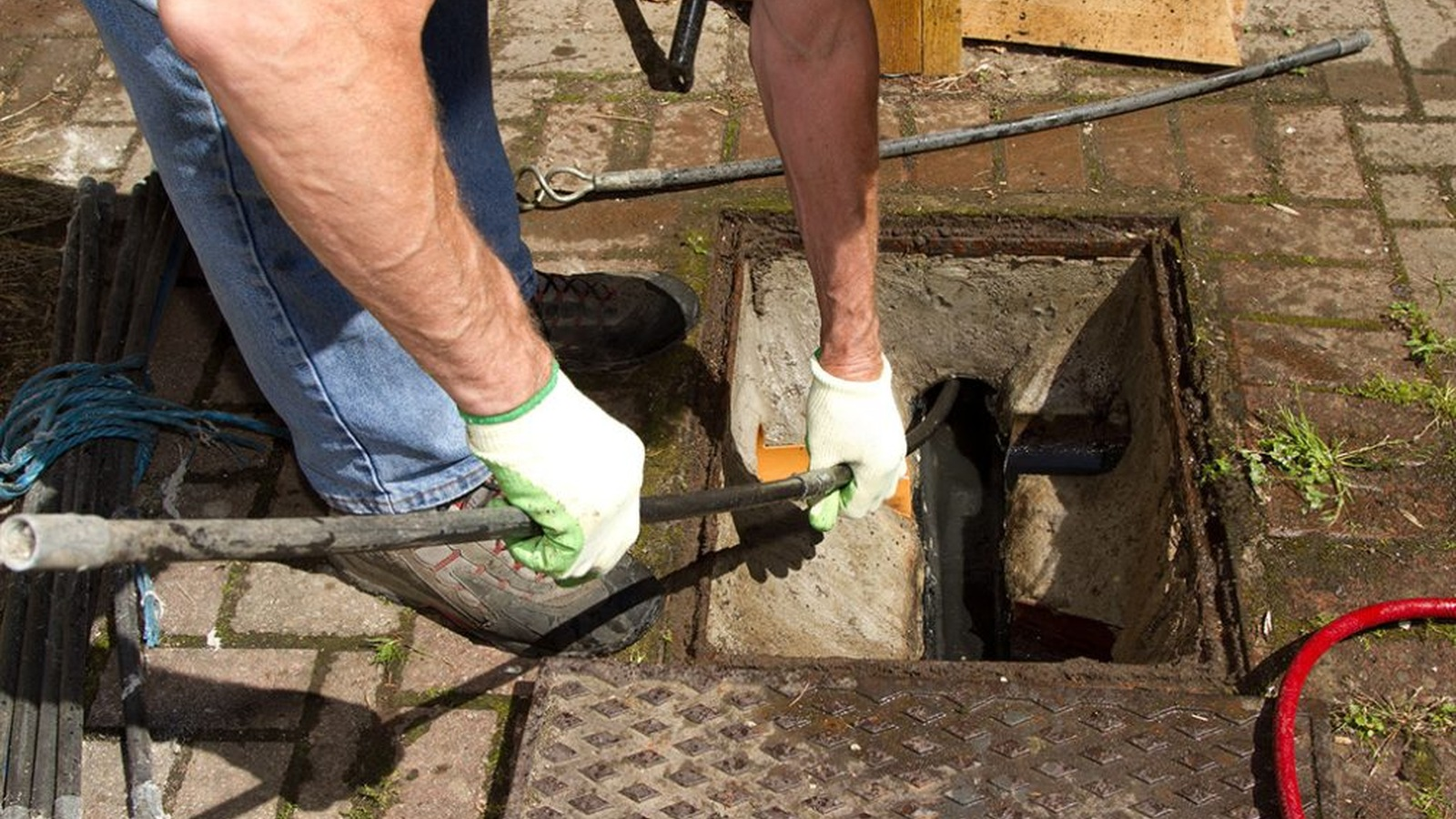 A drainage engineer carrying out urgent work at an external chamber. Image sourced from the Quick Clear Drainage website.